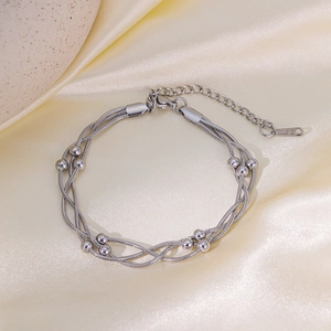 Close-up of multi-layer stainless steel snake chain bracelet with silver beads on silk