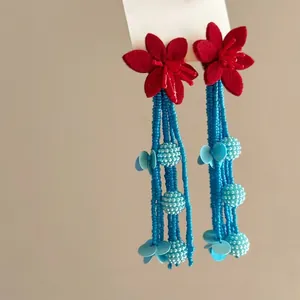 Detailed view of summer pastoral style red flower earrings with long blue beaded tassels