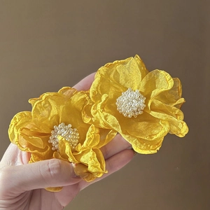 Detailed view of yellow fabric flower earrings with elegant white pearl centers.