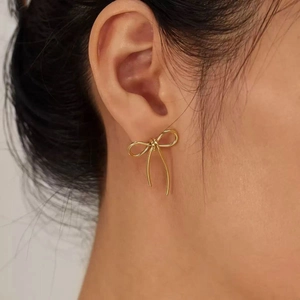 Élégantes boucles d'oreilles nœud papillon en acier doré minimalistes portées