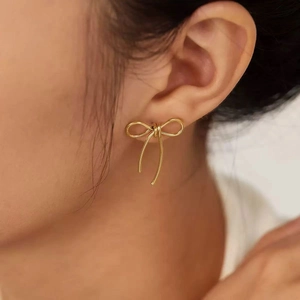Boucles d'oreilles nœud en acier inoxydable doré au design épuré sur modèle