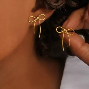 Gros plan détaillé des boucles d'oreilles nœud en acier doré portées pour le style