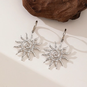 Detailed macro view of silver sun spiral earrings with hammered metal texture