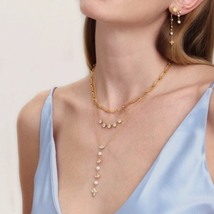 Detailansicht einer eleganten mehrlagigen Goldkette mit Zirkonia und Perlen an Model.
