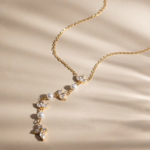 Detailaufnahme einer goldenen Halskette mit weißen Perlen und Zirkon