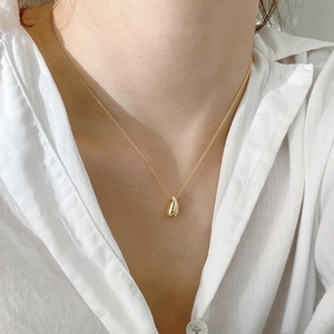 Détail d'un pendentif goutte d'eau minimaliste en or 18 carats sur une chaîne raffinée