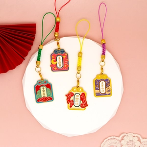 Vista dettagliata di quattro ciondoli omamori cinesi colorati con frasi di benedizione.