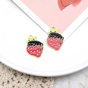 Detailopname van schattige emaille hangers met kat en aardbei voor maken van sieraden.