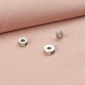 Detailed macro view of three stainless steel gear-patterned jewelry spacer beads