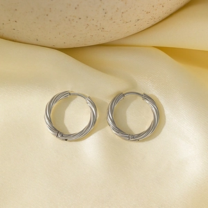 Boucles d'oreilles torsadées en acier argenté sur un fond en soie luxueuse