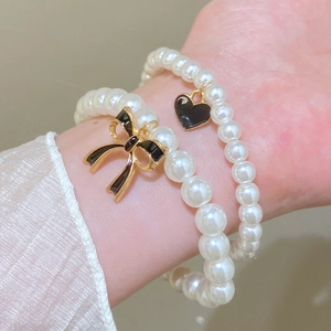 Handmade beaded stretch bracelet set with white pearls and black bow heart charms