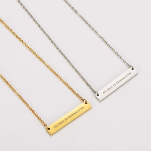 Primer plano de collares con colgante de barra dorada y plateada con grabado navideño