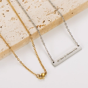 Primer plano de collar con colgante de barra de acero inoxidable y grabado navideño