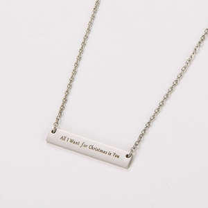 Primer plano del grabado 'All I Want for Christmas is You' en un collar de barra de acero