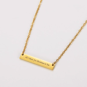 Vista detallada de un collar de barra chapado en oro de 18k con texto grabado festivo