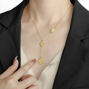 Collier trèfle doré en Y avec gravure soleil porté par un mannequin en veste élégante
