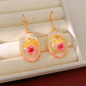 Close-up of elegant resin drop earrings with real dried flowers in a jewelry box