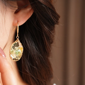 Detail showing natural dried flowers encapsulated in oval resin earrings with gold hooks
