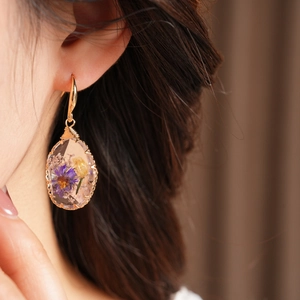 Detail view of elegant teardrop resin earrings featuring embedded colorful dried flowers