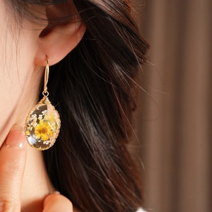 Close-up detail of elegant oval resin drop earrings featuring real yellow dried flowers
