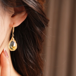 Close-up of elegant teardrop resin earrings featuring a delicate yellow flower inside