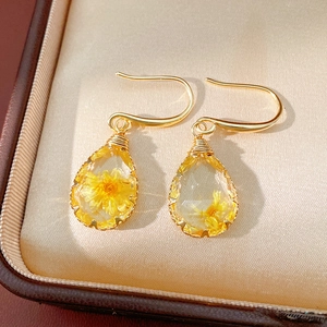 Detail of pastoral resin teardrop earrings with yellow dried flowers and gold hooks
