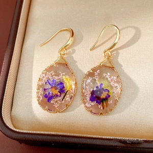 Detailed view of elegant oval resin earrings featuring colorful dried flowers inside