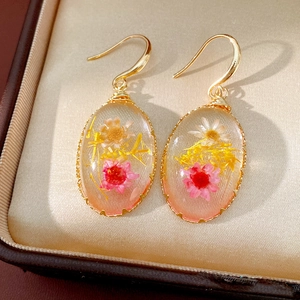 Detailed view of pastoral oval resin earrings with delicate real dried flowers inside hooks