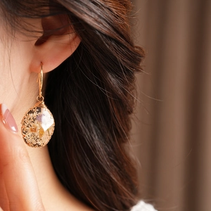 Close-up of pastoral style resin teardrop earrings with dried flowers on model's ear