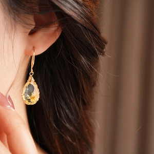 Close-up detail of a teardrop resin earring with a yellow dried flower and gold wire wrap