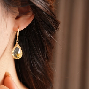 Close-up of teardrop resin earring with embedded flower on gold hook