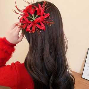 Nahaufnahme einer leuchtend roten Spinnenlilien-Haarspange auf langem dunklem Haar