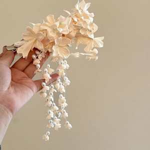 Detailansicht einer cremefarbenen Blumenhaarklammer mit eleganten, hängenden Perlenquasten