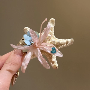 Makroansicht der zarten rosa Spinnenlilie und des Seestern-Details auf dieser retro Haarspange