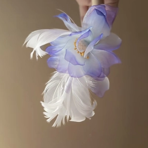 Makrodetail einer romantischen lila Blumen-Haarklammer mit weichen weißen Federn
