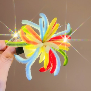 Detailansicht einer bunten Plüschblumen-Haarklammer mit leuchtenden LED-Lichtern
