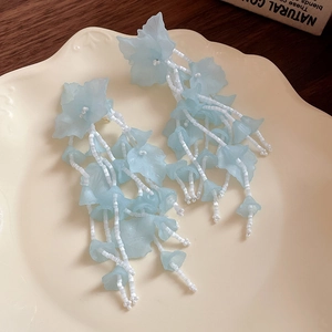 Eleganti orecchini a fiore blu con lunghe nappe di perline bianche per signora.