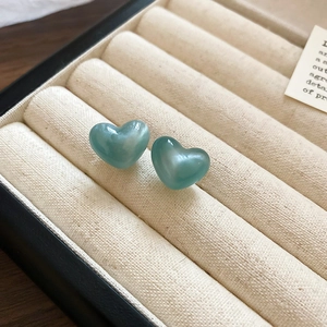 Macro view of blue heart-shaped stud earrings with a marbled texture in a jewelry box