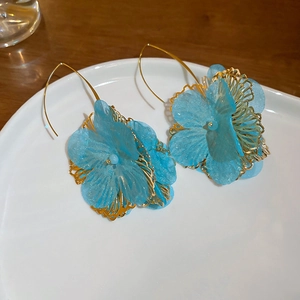 Detail view of elegant blue fabric cluster flower petal earrings on white plate
