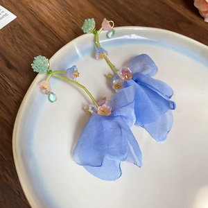 Detail view of elegant blue fabric flower earrings with delicate green beaded stems.