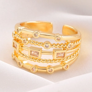 Detailed macro view of a multi-layer gold geometric ring with sparkling zircon inlays.