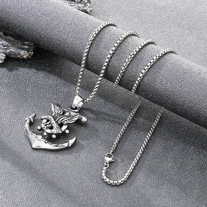 Macro view of vintage punk eagle anchor pendant on a textured dark rock background.
