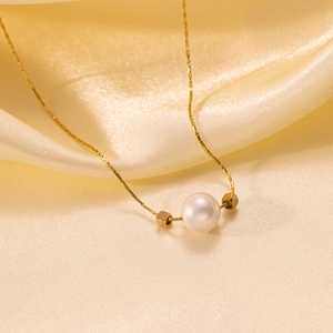 Minimalist gold necklace featuring a white pearl and square beads on silk background