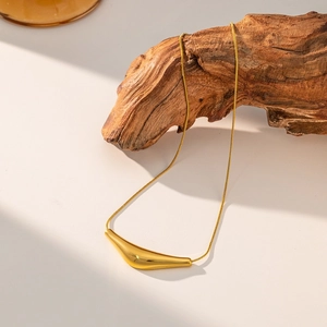 Minimalist gold-plated stainless steel curved pendant necklace on a wooden display