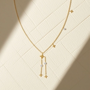 Collier Y doré avec pendentifs étoiles et zircons brillants sur une surface texturée