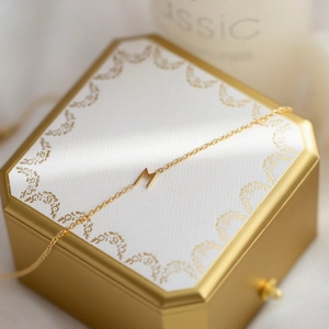 Collier élégant en titane doré avec pendentif lettre M présenté sur un coffret cadeau