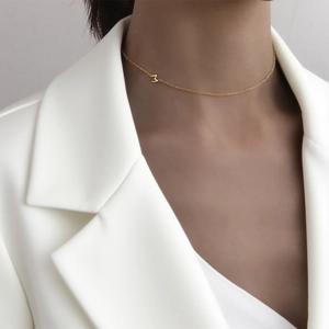 Collier élégant en acier titane doré avec pendentif M, style minimaliste porté par un mannequin