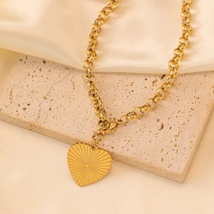 Gold heart pendant necklace with sunburst engraving on a chunky vintage chain