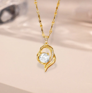 Detail of 18k gold heart pendant featuring a large center stone and pavé accents