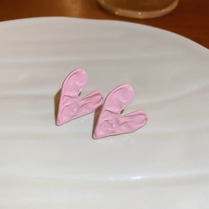 Detailed macro view of pink textured heart-shaped stud earrings on a white plate